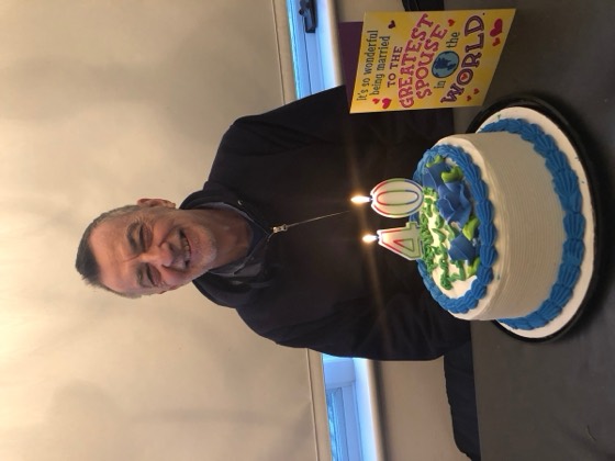 Larry at his 40th wedding anniversary, smiling behind a birthday cake